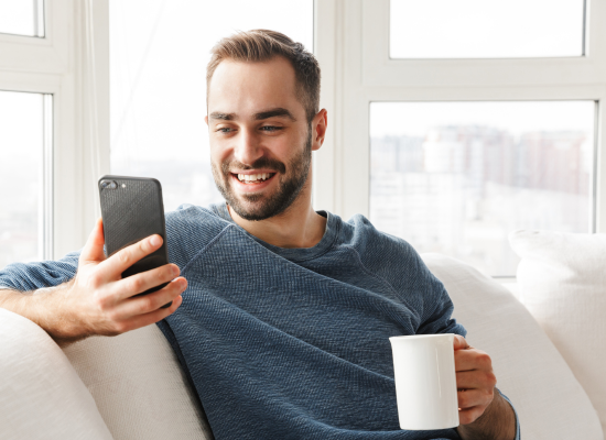 man drinking coffee and looking at cellphone