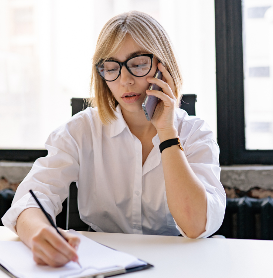 woman speaking on phone and taking notes